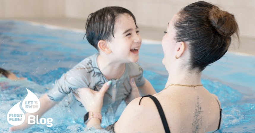 Mama hält ihren lachenden Sohn beim Babyschwimmkurs im Wasser – spielerische Wassergewöhnung und sichere erste Schwimmerfahrungen.