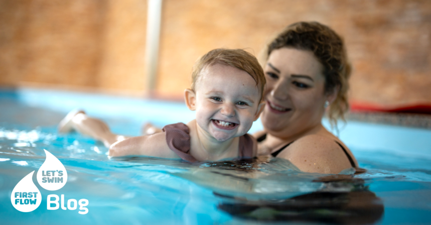 Mama hält ihre Tochter im Wasser beim Babyschwimmkurs